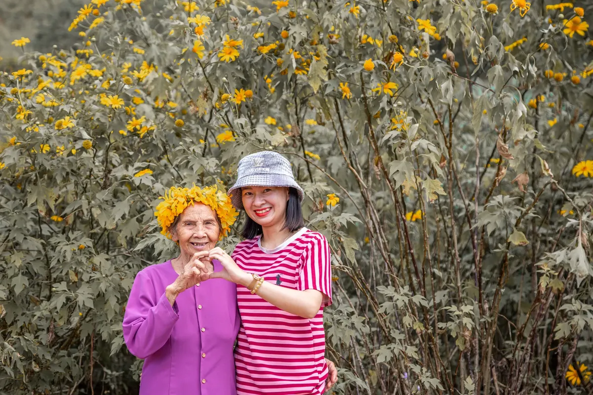 Grandmother and granddaughter sharing a joyful moment in a flower garden in Vietnam.