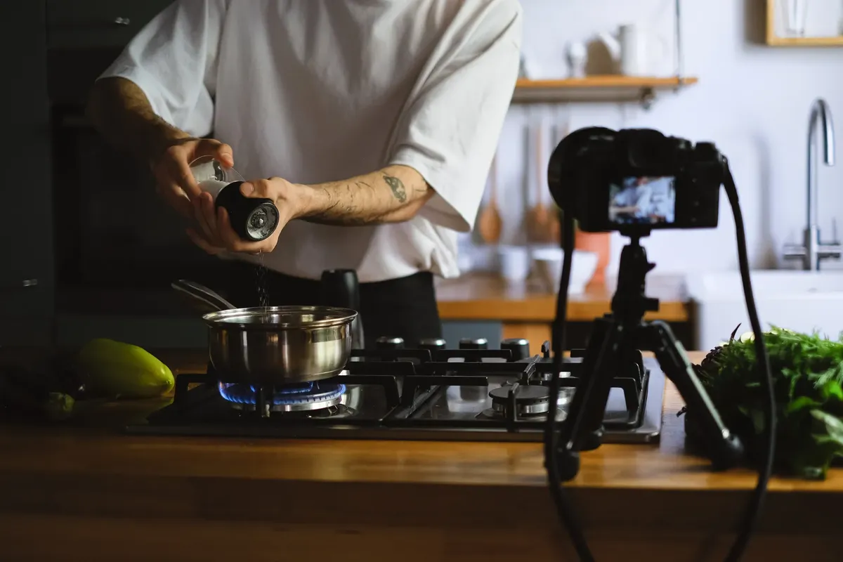 一個人在現代廚房裡用 stove 装飾食物，同時錄製烹飪vlog。