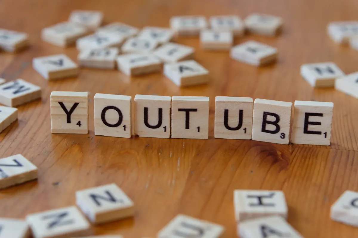 목재 표면에 'YOUTUBE'를 쓴 목재 글자 타일, 동영상 공유 및 스트리밍을 상징합니다.