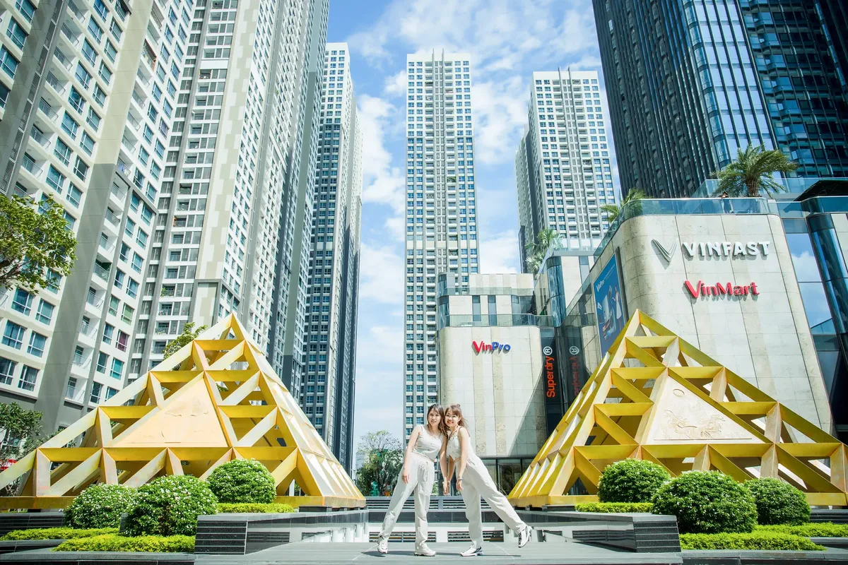 Two women posing in front of modern skyscrapers in Ho Chi Minh City, Vietnam.