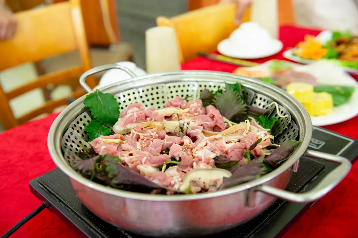 Delicious Vietnamese hotpot featuring fresh vegetables and slices of pork, captured in Hanoi, Vietnam.