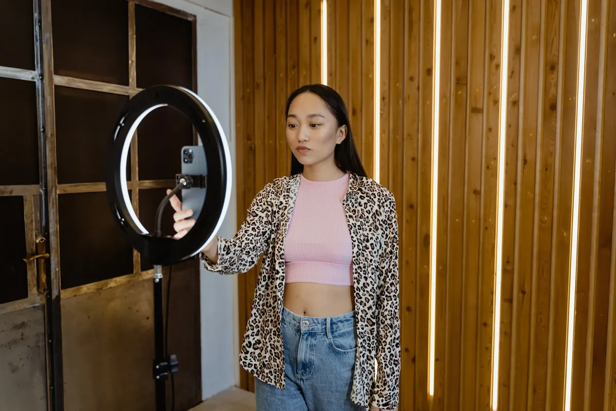 An asian woman influencer filming a vlog with a ring light in a stylish indoor setting.
